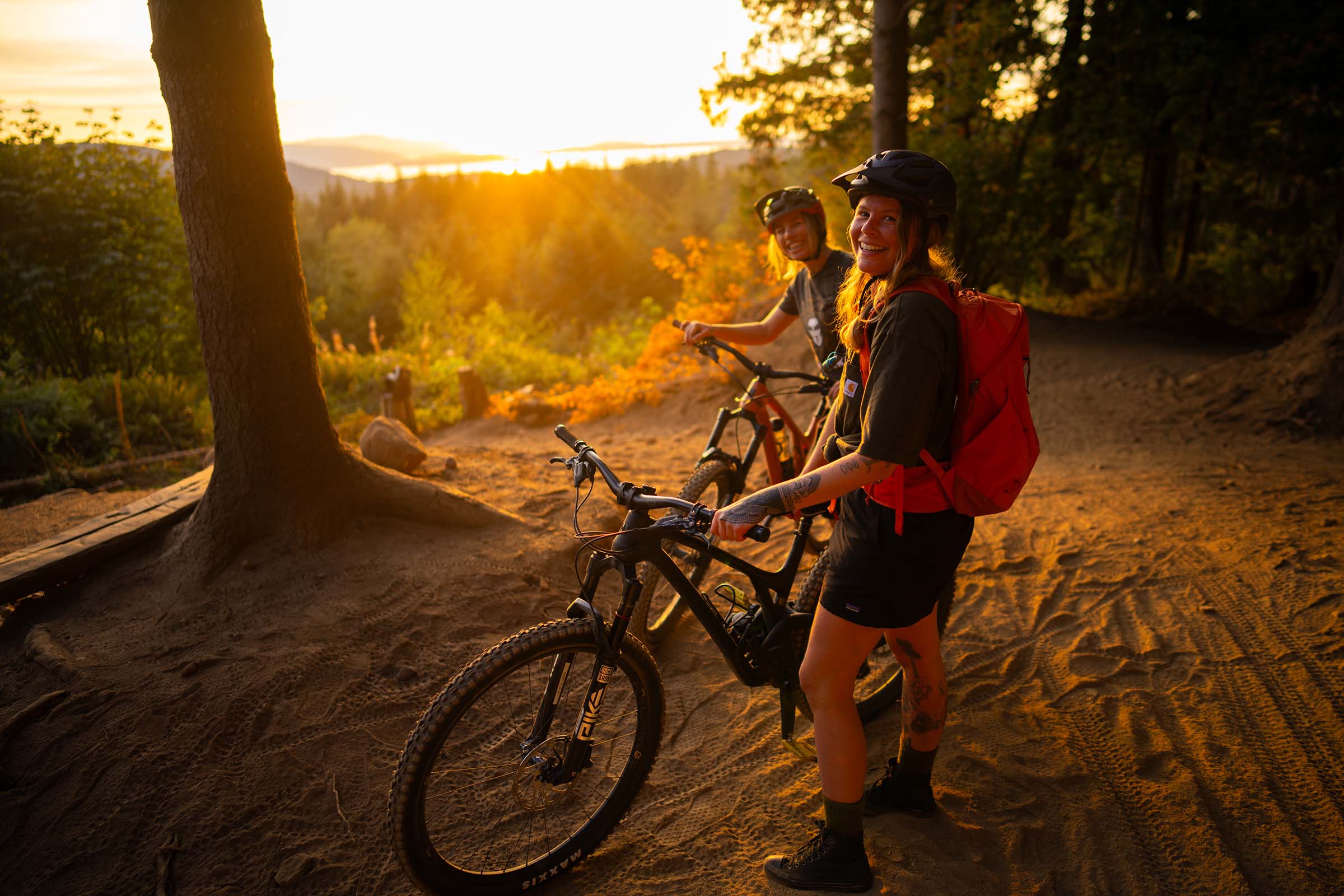 Two riders laughing at a trailhead overlook at golden hour